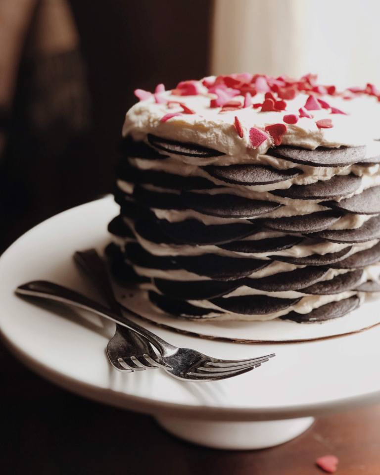 A chocolate icebox cake on a cake stand, made of alternating layers of whipped cream and chocolate wafers